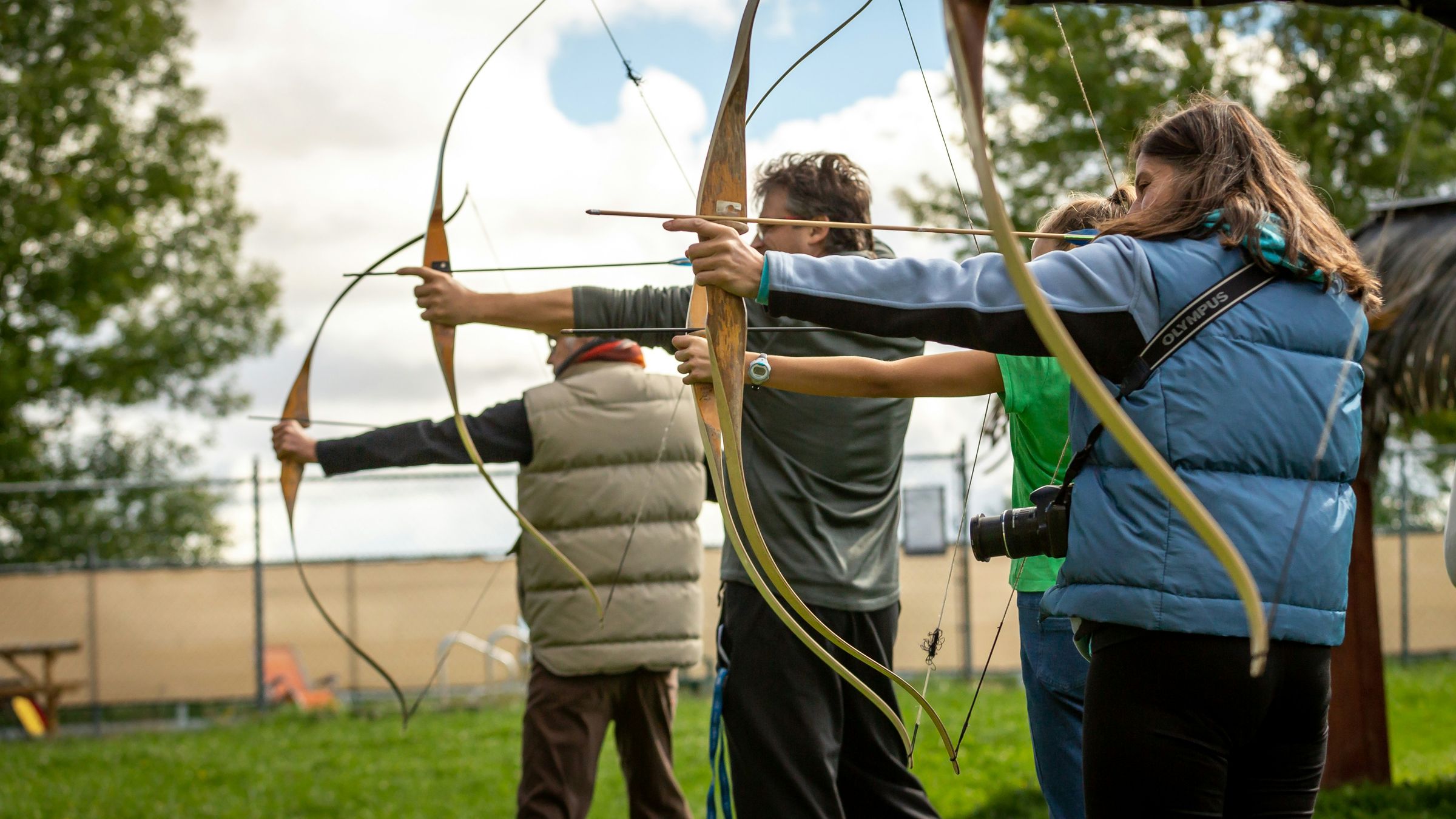 Group of archers drawing recurve bows together on an outdoor range