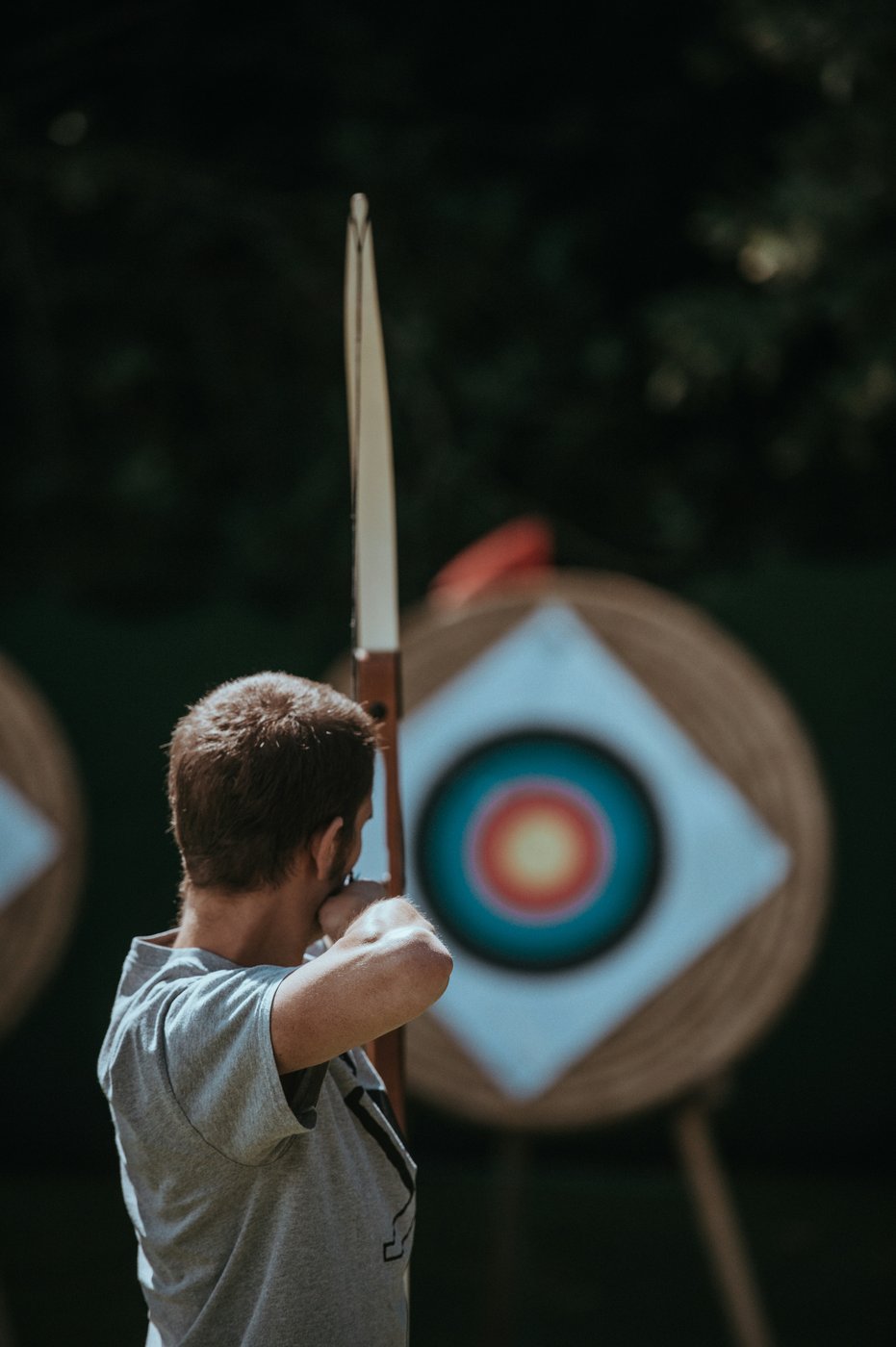 Archer aiming a traditional bow toward a range target