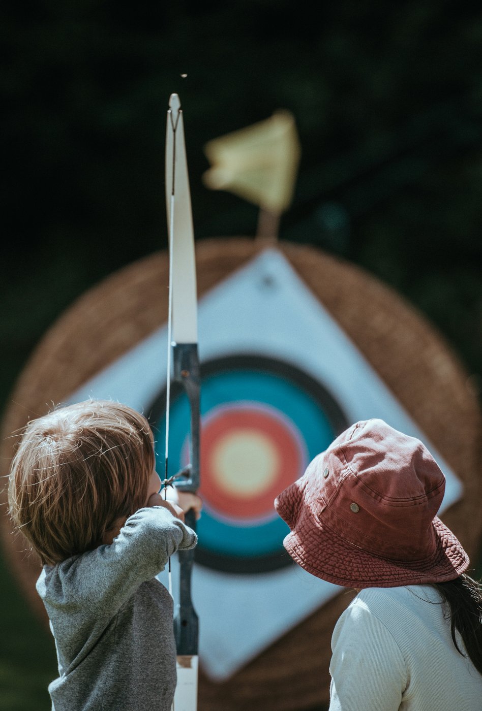 Young archer aiming at a target during a group lesson